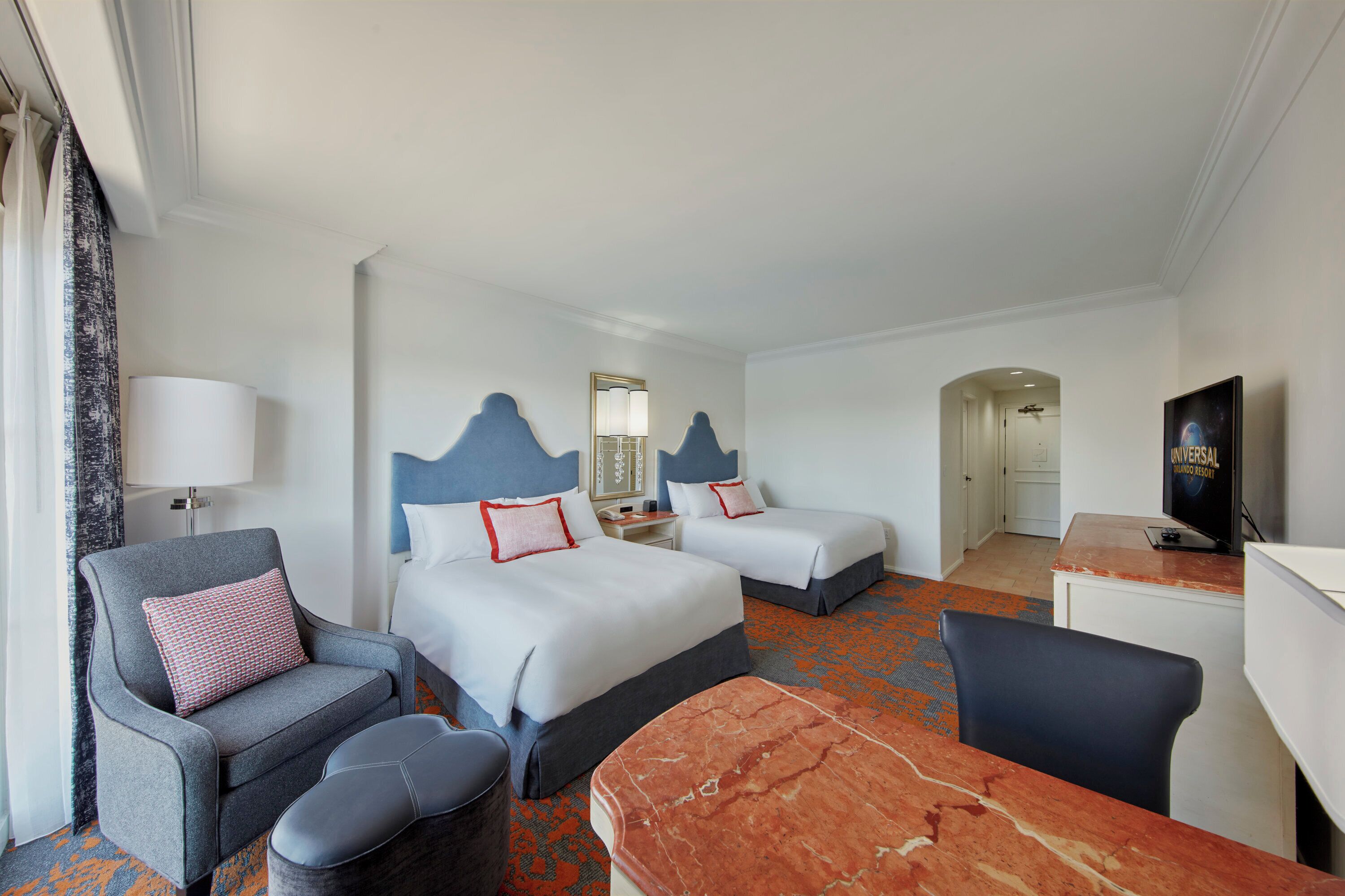 Une chambre d’hôtel avec deux lits, un bureau, une chaise, un canapé et une télévision.