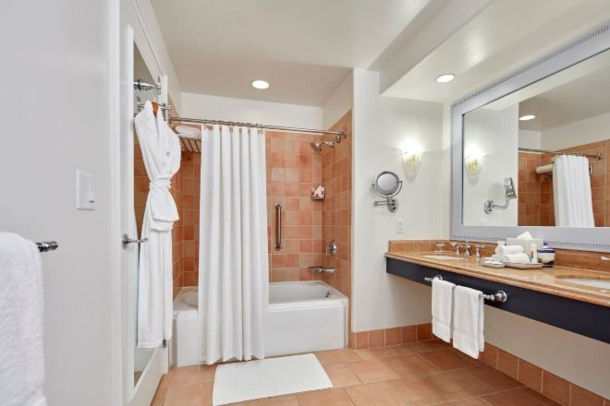 Un baño moderno con bañera, ducha y tocador con un espejo grande.