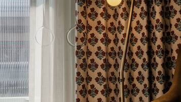 A room with a window, a floor lamp, and a patterned curtain.