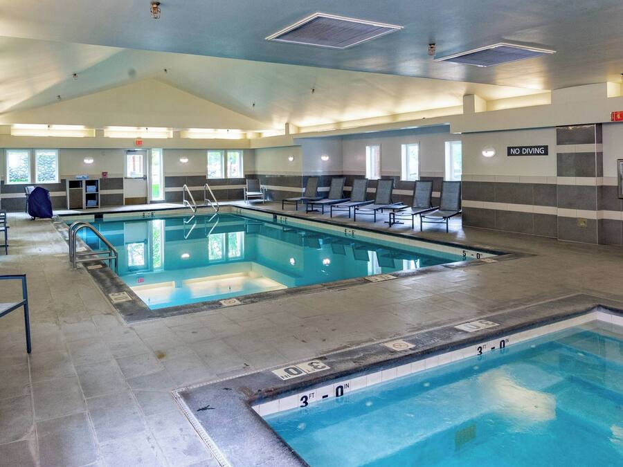 En stor inomhuspool med flera banor, solstolar och en skylt med texten ”Hoppning förbjuden”.