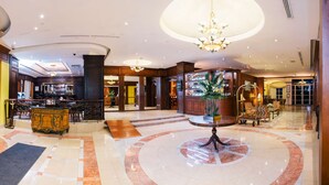 A spacious lobby with a marble floor, a central round table, and a bar area with a display of items. - Hilton Princess Managua (Managua)