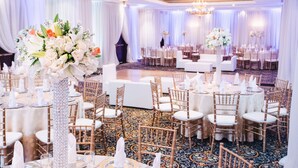 A banquet hall with round tables, white chairs, and floral centerpieces. - Hilton Princess Managua (Managua)