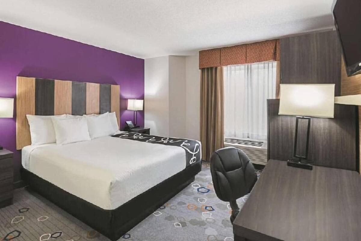 Une chambre d’hôtel avec un lit, des tables de chevet, un bureau et une chaise.