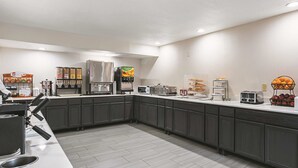 A modern kitchen area with a coffee station, microwave, toaster, and various food dispensers. - La Quinta Inn & Suites by Wyndham Minneapolis Northwest (Brooklyn Park)