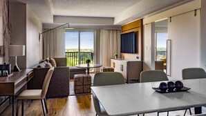 Una habitación de hotel moderna con balcón, comedor y televisor.