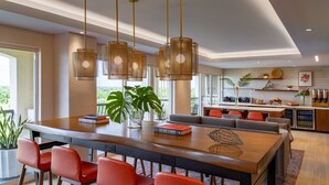 Una cocina moderna con una isla grande, sillas rojas y lámparas colgantes.