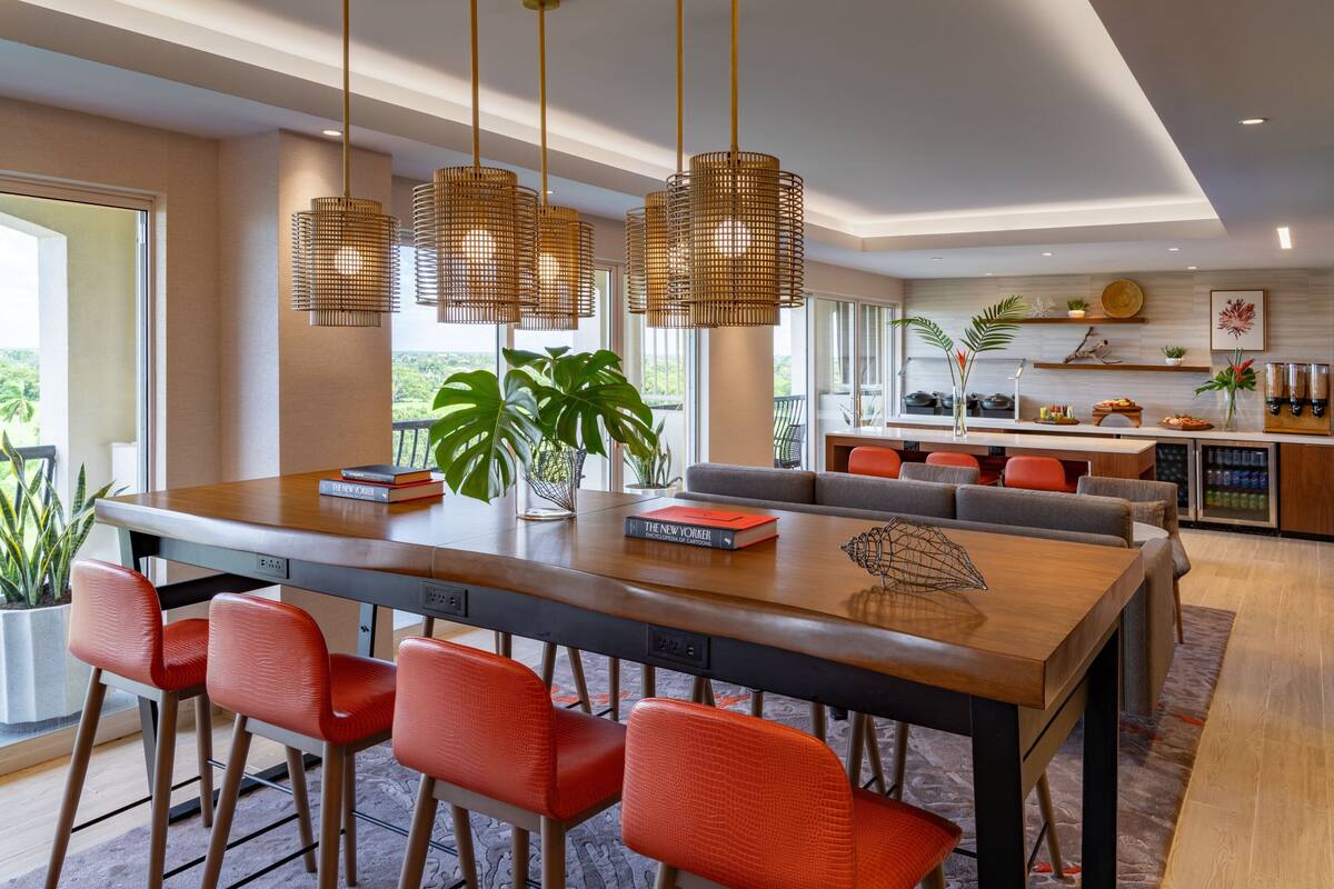 A modern kitchen with a large island, red chairs, and hanging pendant lights.