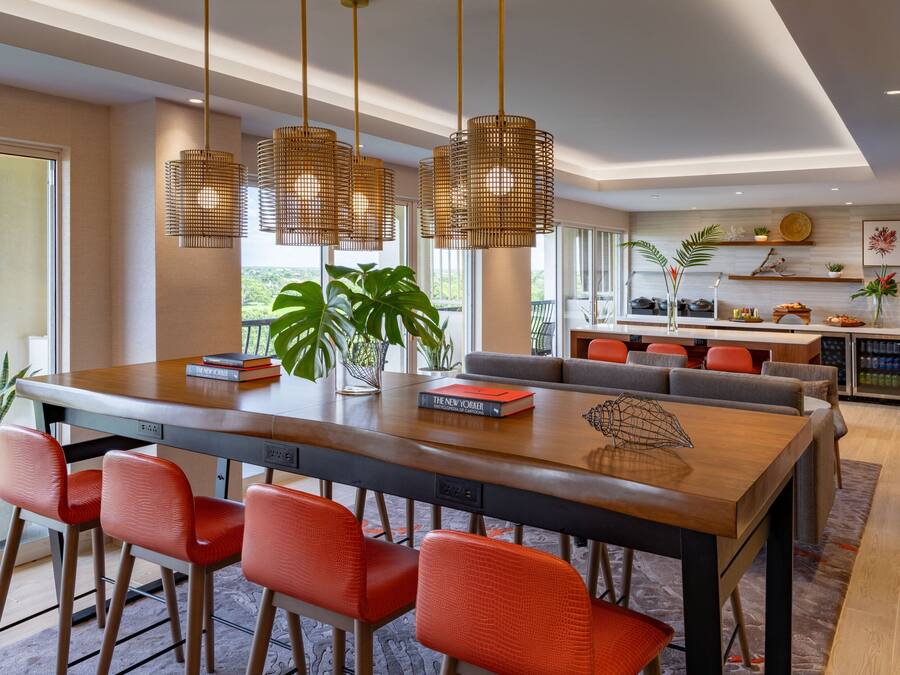 A modern kitchen with a large island, red chairs, and hanging pendant lights.