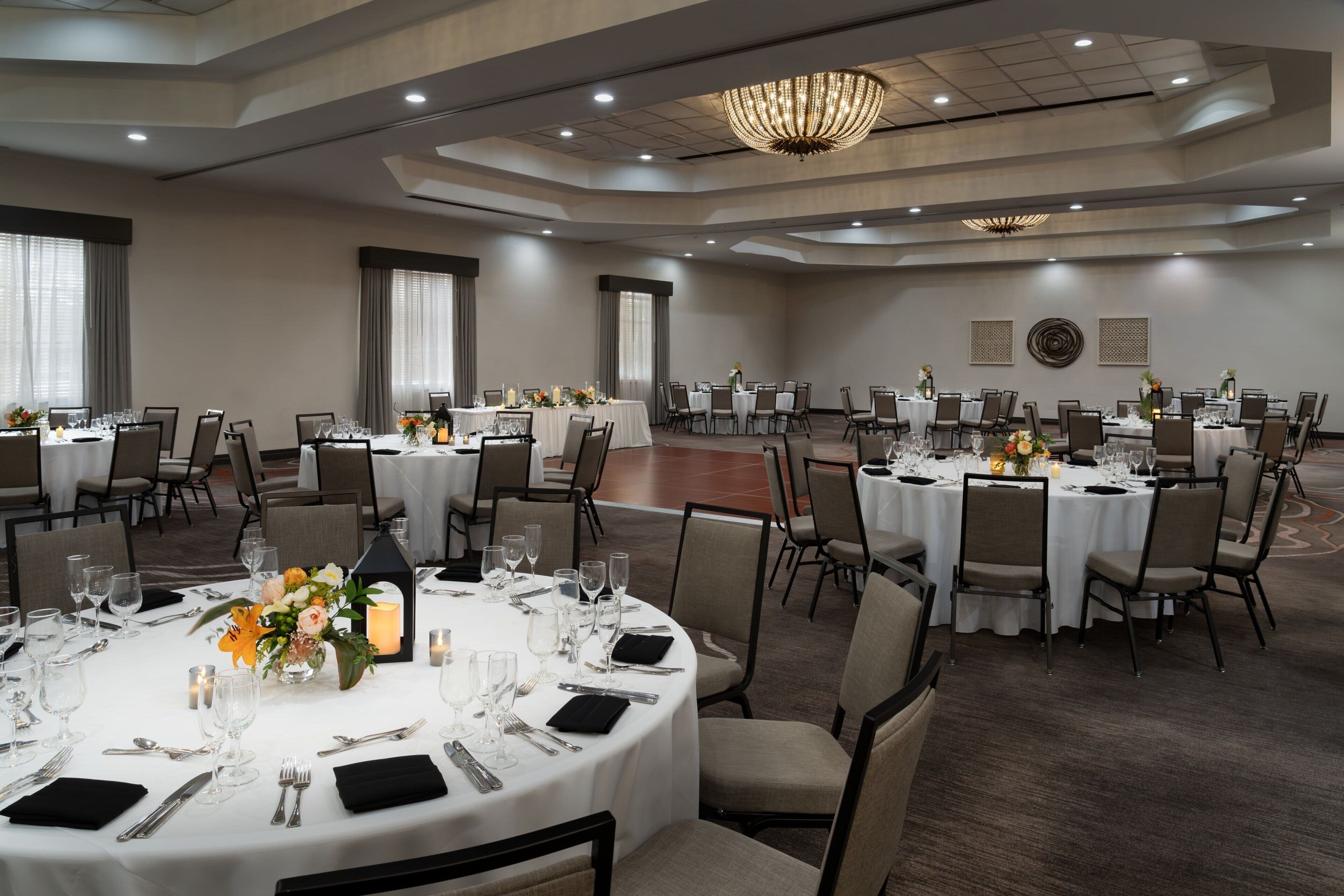 Un salón de banquetes con mesas redondas dispuestas para una cena, con manteles blancos, sillas y centros de mesa.