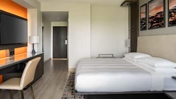 A modern hotel room with a bed, a desk, and a TV.