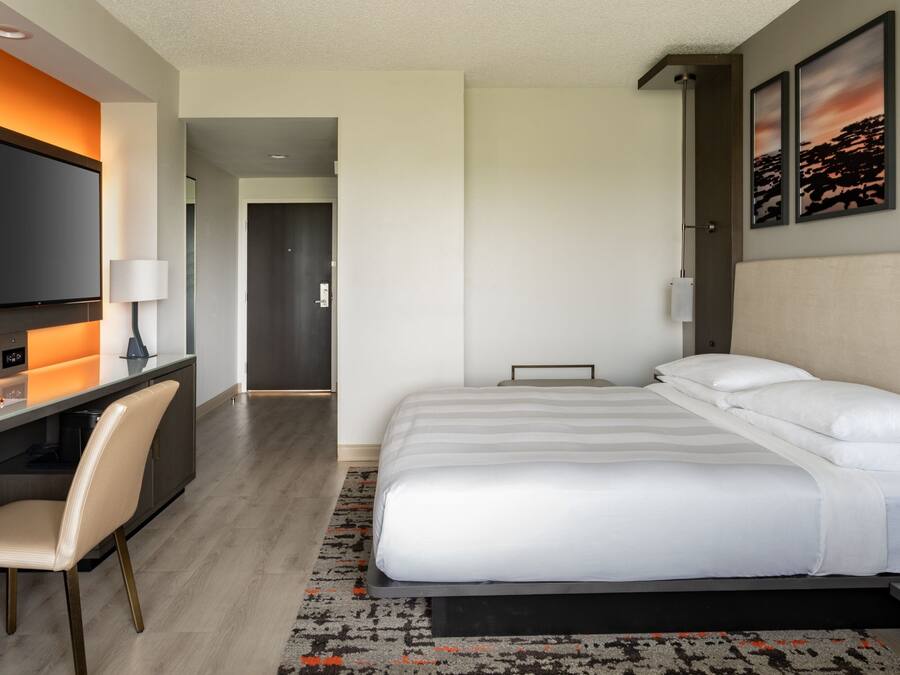 A modern hotel room with a bed, a desk, and a TV.