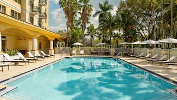 Alberca al aire libre, sombrillas en la alberca y camastros