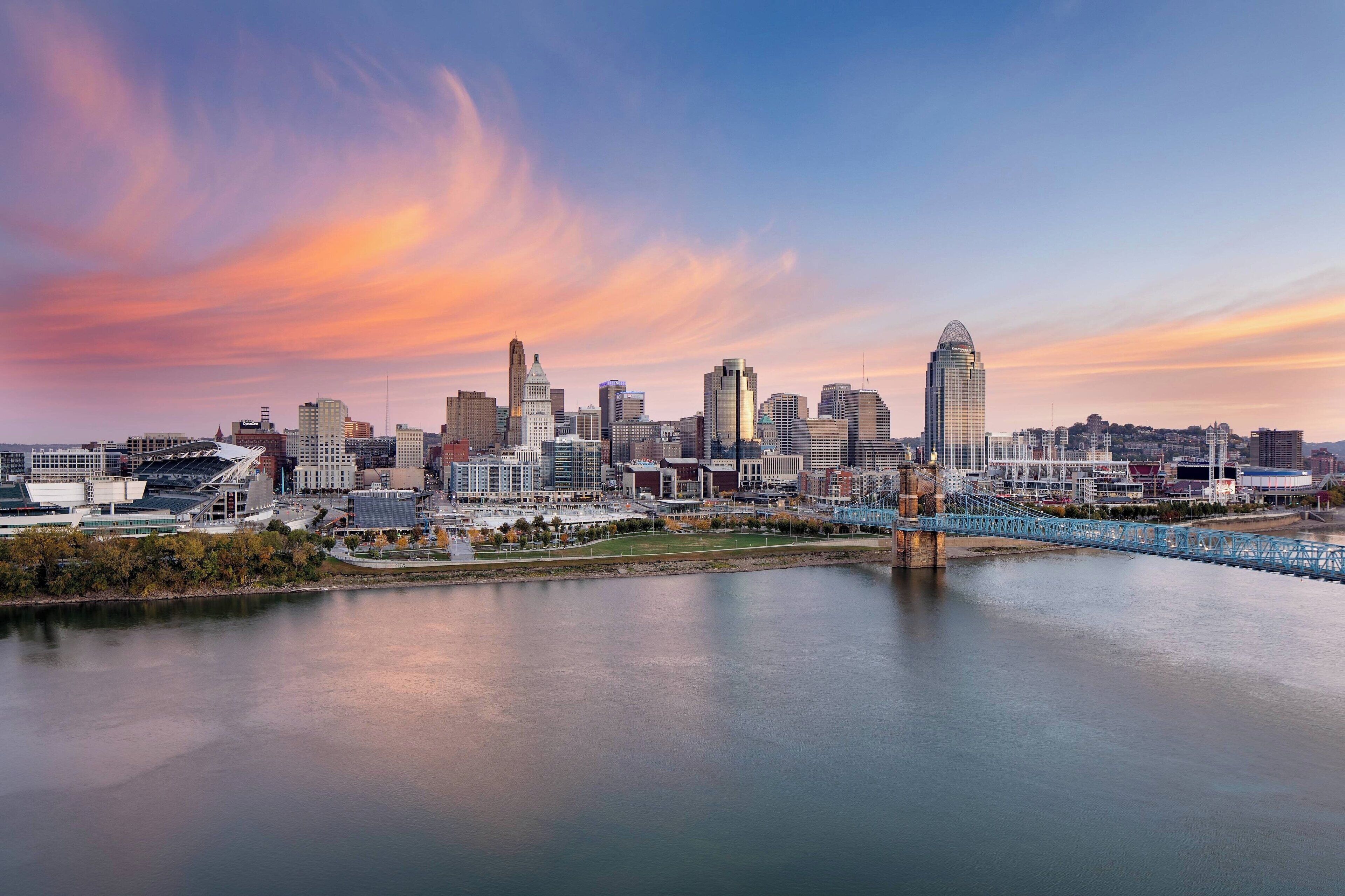 A city skyline with modern buildings, a river, and a bridge.