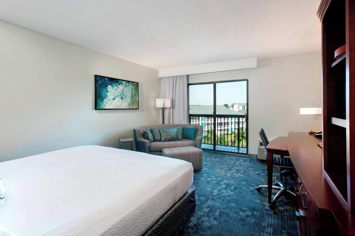 Une chambre d’hôtel avec un grand lit, un canapé, un bureau et un balcon avec vue.