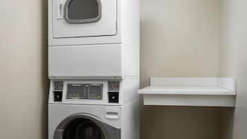 A stacked washer and dryer unit with a control panel and a small shelf above it.