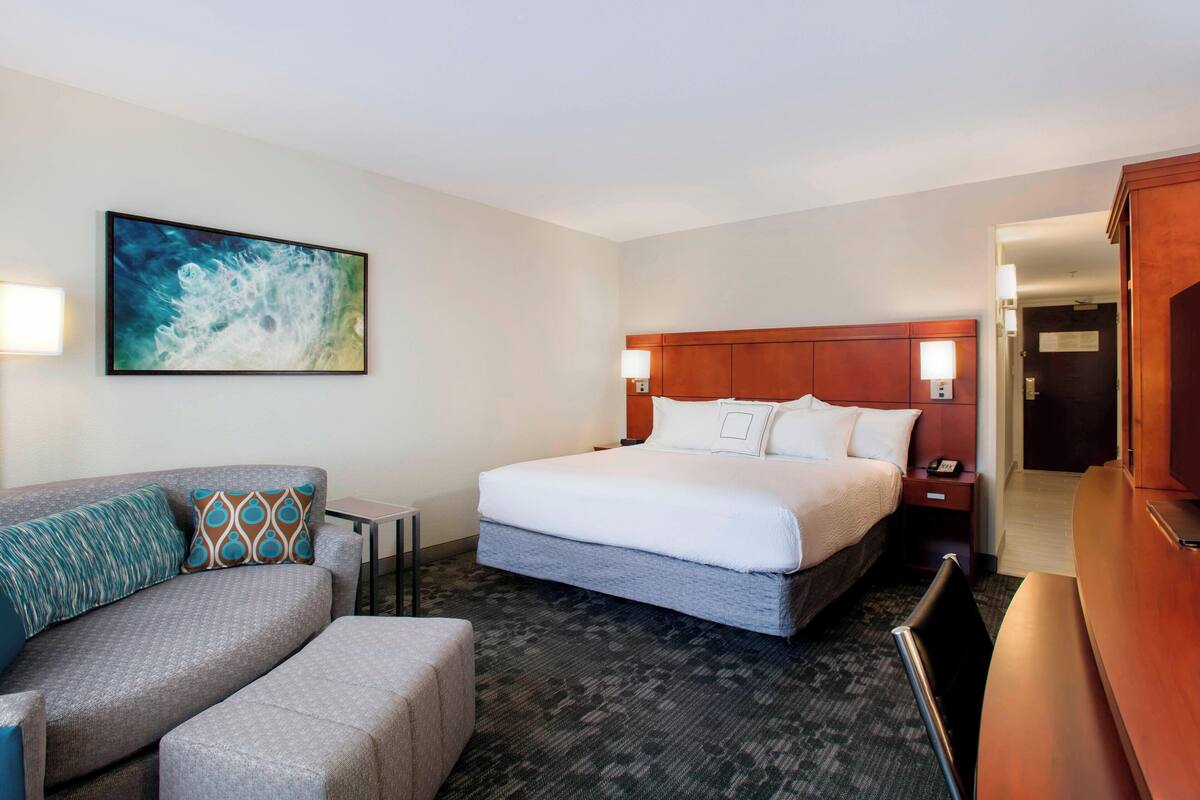 Une chambre d’hôtel avec un lit, un canapé, un bureau et un tableau au mur.