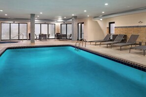 Relax by the pool surrounded by a tiled deck and lounge chairs.