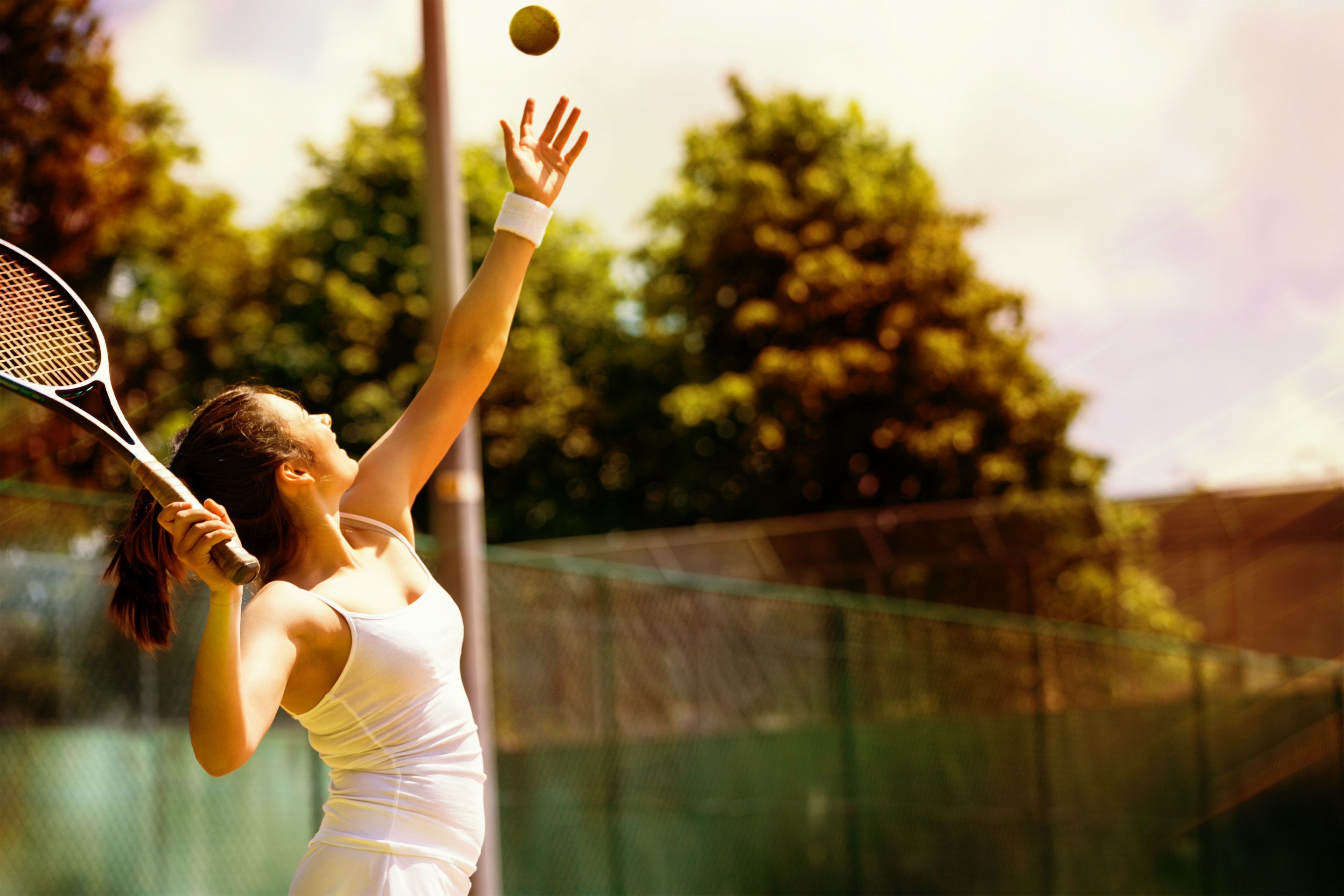 A tennis player in a white outfit on a tennis court.