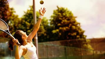 A tennis player in a white outfit on a tennis court.