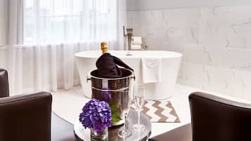 A modern bathroom with a bathtub, a champagne bottle, and a glass on a tray.