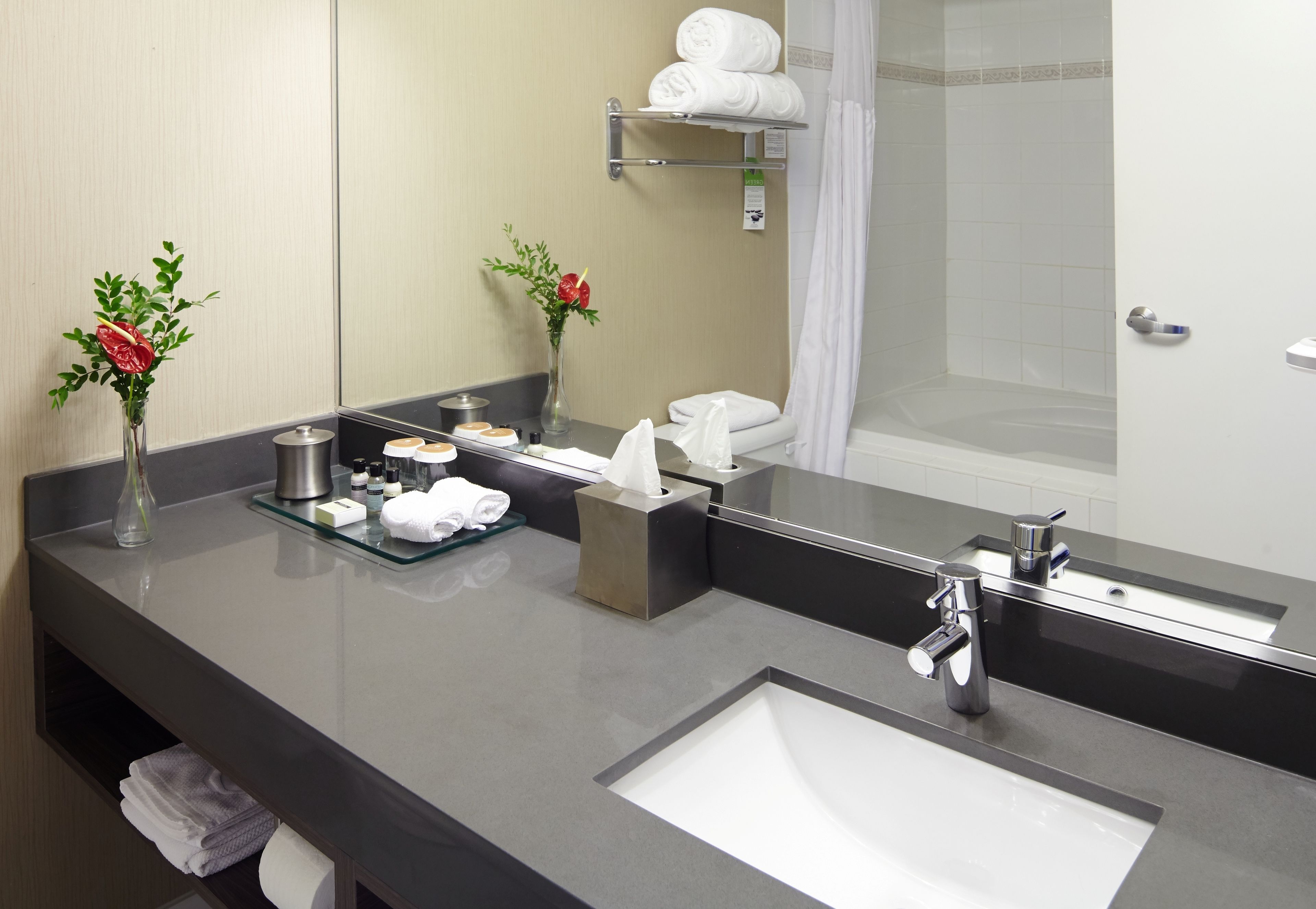 A modern bathroom with a large mirror, a sink, and a shower area.