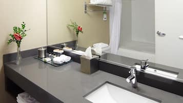 A modern bathroom with a large mirror, a sink, and a shower area.