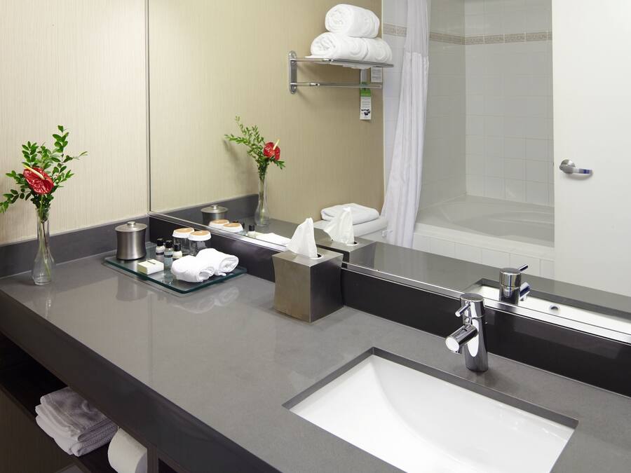 A modern bathroom with a large mirror, a sink, and a shower area.