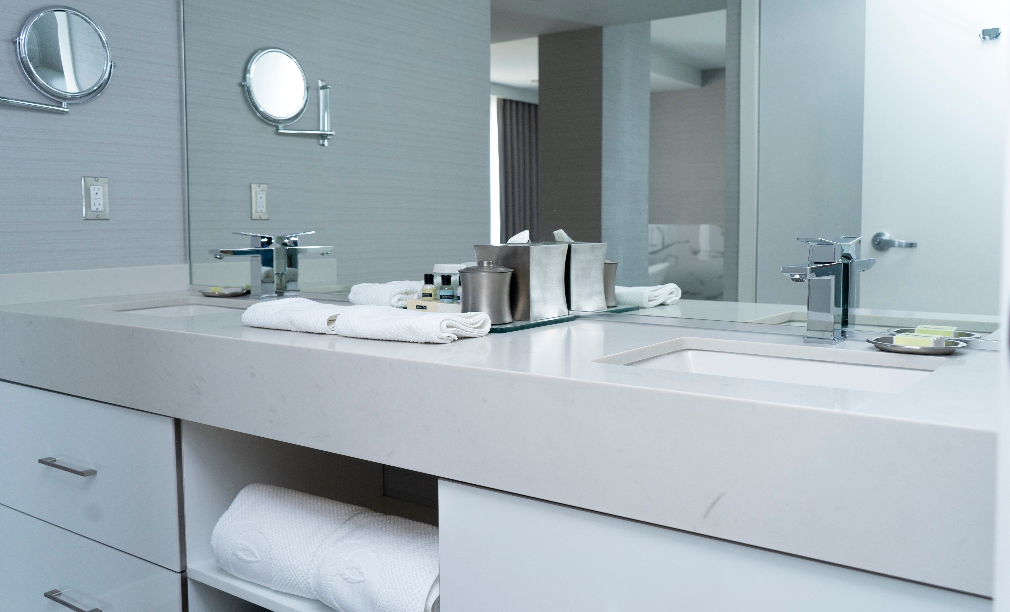 A modern bathroom with a large mirror, two sinks, and a towel rack.