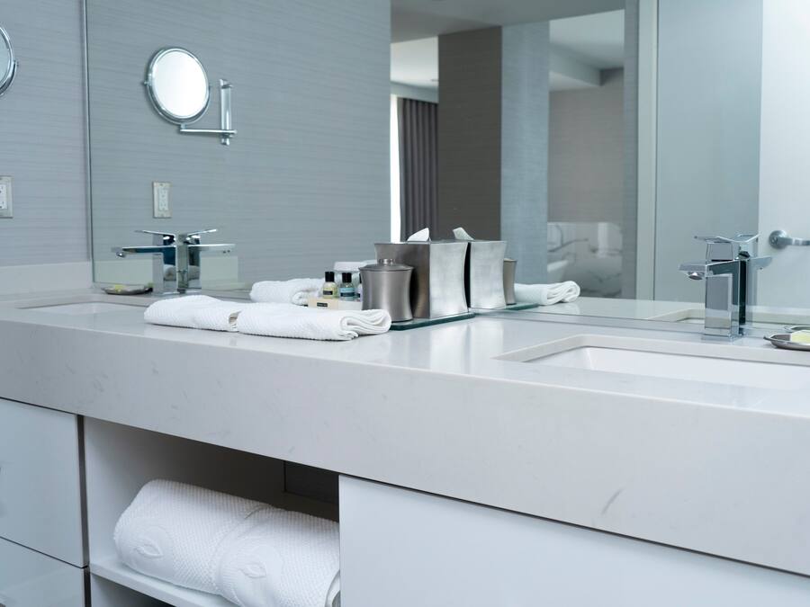 A modern bathroom with a large mirror, two sinks, and a towel rack.
