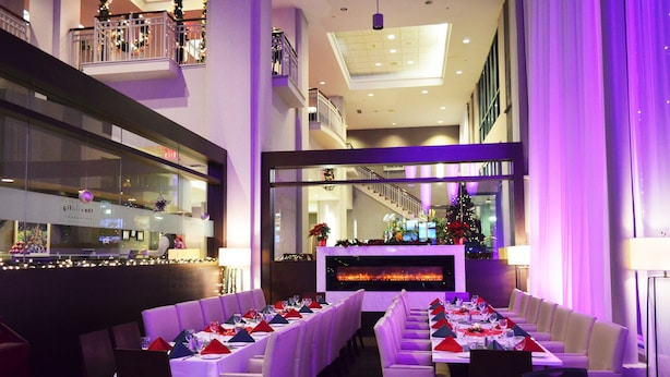 A restaurant with white booths and a long table, a fireplace, and a Christmas tree.