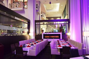 A restaurant with white booths and a long table, a fireplace, and a Christmas tree. - Executive Plaza Hotel Metro Vancouver (Coquitlam)