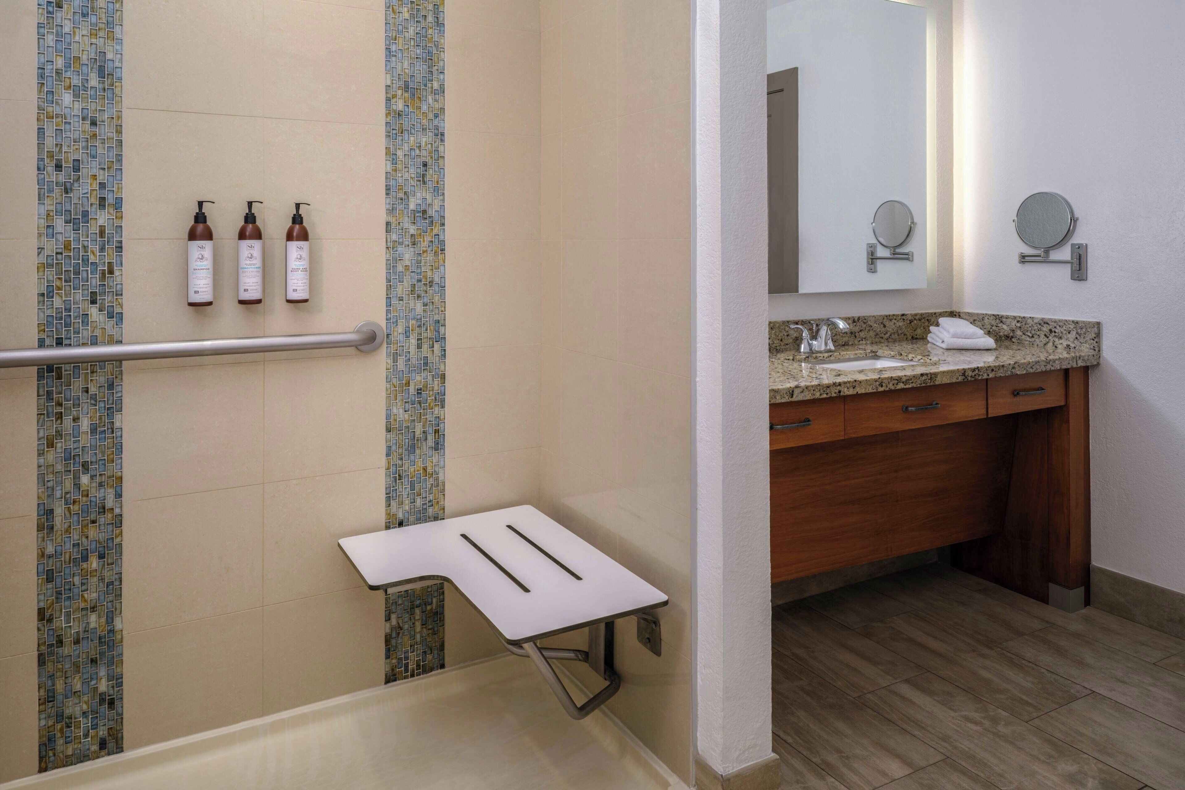 A bathroom with a shower, a sink with a mirror, and toiletries on the wall.