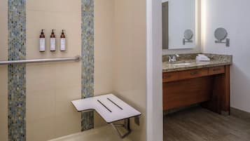 A bathroom with a shower, a sink with a mirror, and toiletries on the wall.