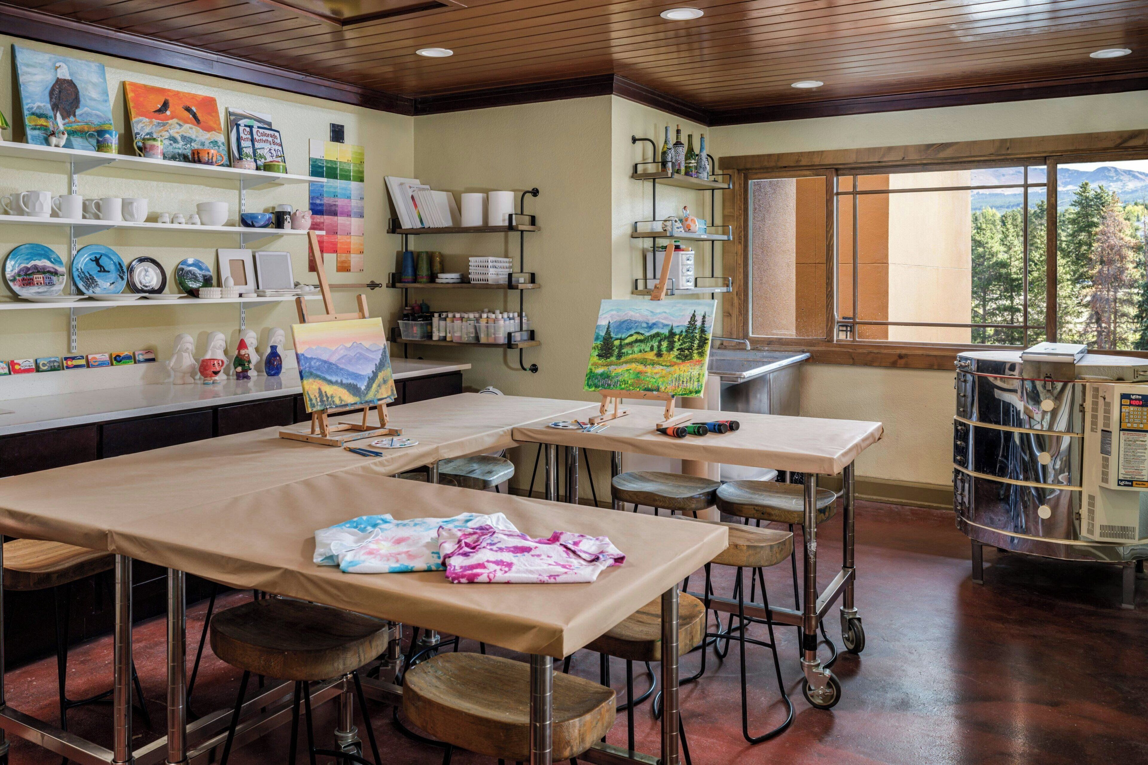A studio with easels, art supplies, and paintings on display.