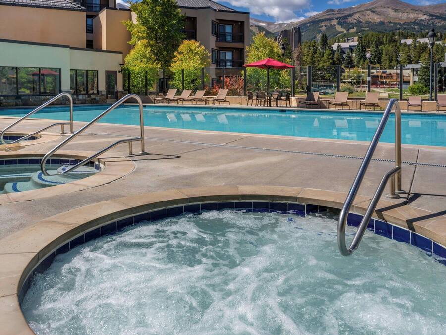 A hot tub area with a pool, lounge chairs, and a mountain view.