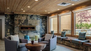 A modern lounge area with sofas, a coffee table, and a stone wall with a fireplace.