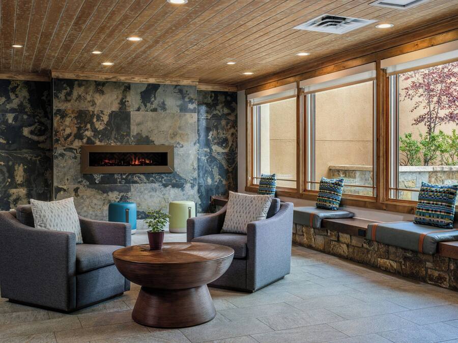 A modern lounge area with sofas, a coffee table, and a stone wall with a fireplace.