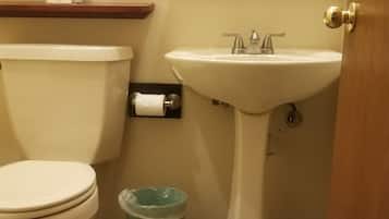 Un baño con inodoro, lavabo y un cubo de basura azul.