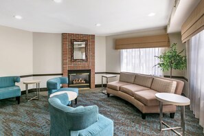 A modern living room with a fireplace, two sofas, a coffee table, and a large window with curtains.