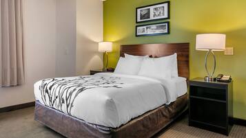 A hotel room with a large bed, two bedside tables with lamps, a wooden headboard, and green walls.
