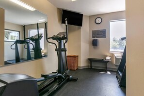 A fitness center with exercise equipment, a TV, a clock, and a window with a view.