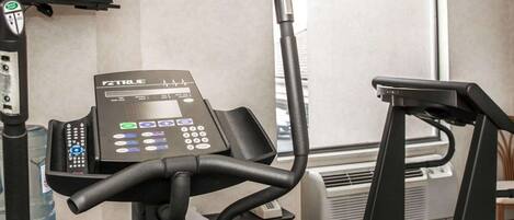 Un gimnasio con cinta de correr, bicicleta estática y monitor de frecuencia cardíaca.