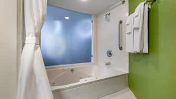 A modern bathroom with a large bathtub, a shower, and a green accent wall.