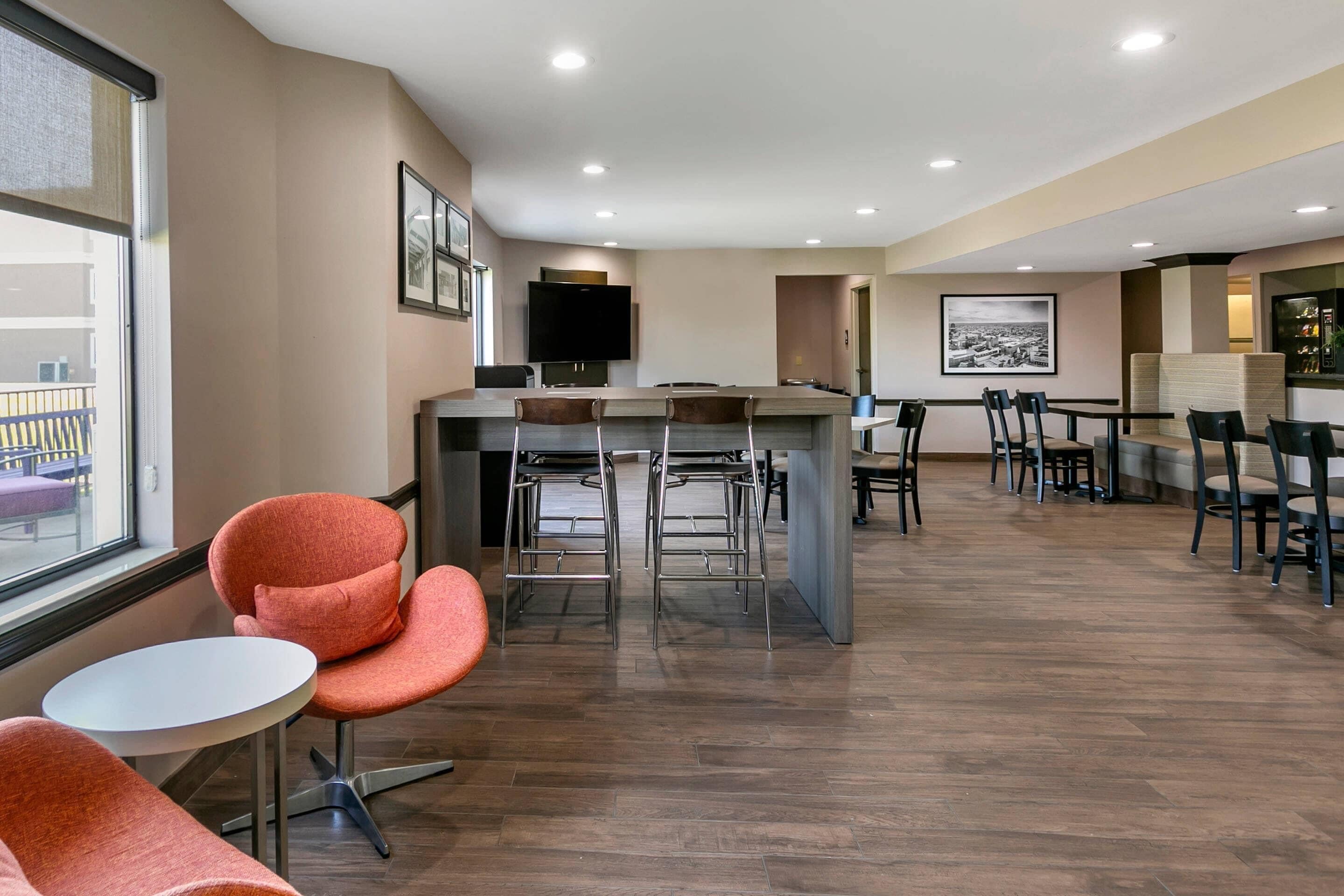 A modern hotel lobby with a bar area, seating arrangements, and a large window providing a view of the outside.