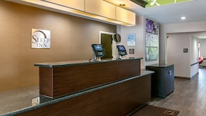 A reception desk with a sign reading "Sleep Inn." There are two digital kiosks on the counter.