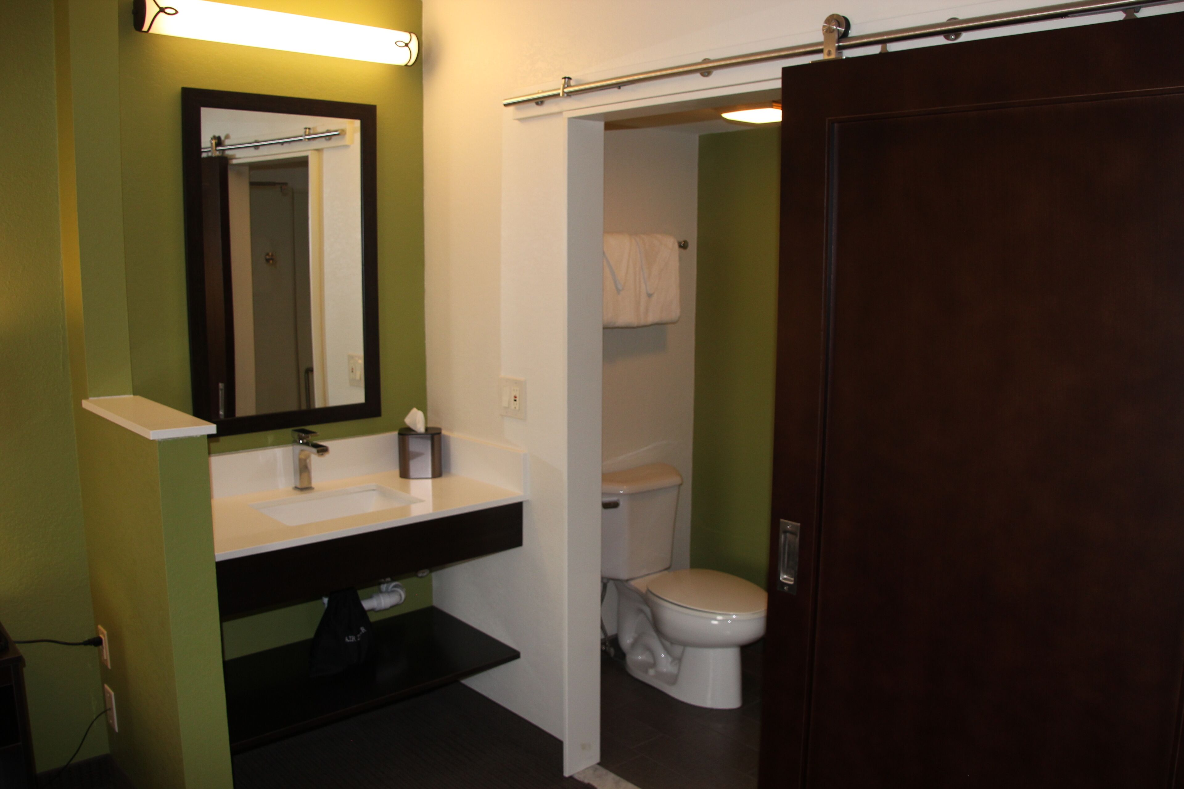 A bathroom with a white sink, a mirror, and a toilet.