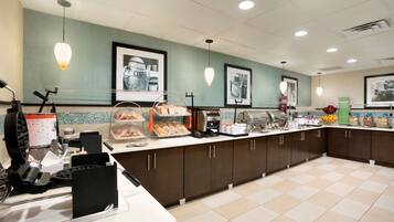 A breakfast bar with various food items, a coffee machine, and a juice dispenser.