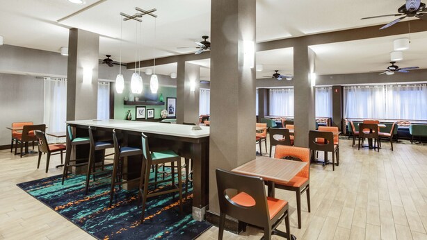 Ein geräumiger Essbereich mit hohen Tischen und Stühlen, eine zentrale Bar und Deckenventilatoren.