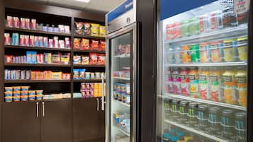 A grocery store with shelves stocked with various snacks and beverages, including a freezer section with frozen drinks.
