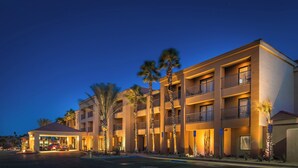 A multi-story hotel with balconies, palm trees, and a well-lit entrance. - Courtyard by Marriott Palm Desert (Palm Desert)